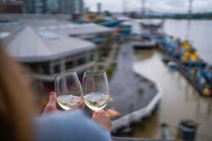 Couple on balcony looking over boardwalk wiith a glass of wine