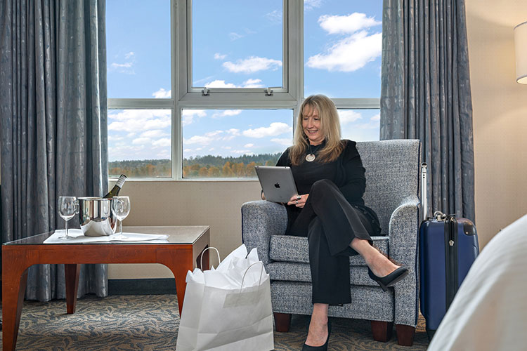 Person working on computer next to shopping bags and wine chilling with 2 glasses